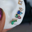 Picture of a variety of earring studs on a white silicon ear. Including the emerald diamond drip studs. 