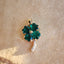 A emerald pendant with four heart shaped emeralds and a beaded center. The stem is made of white gold. 