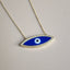 An elongated evil eye pendant with hand painted blue enamel and white eye. The pendant has a pave halo and attached to a thin cable chain. 