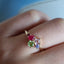 Showing the colored gemstone cluster ring on hand. This ring has different shaped colored gemstones curated into on cluster. Set on a thin gold band. 