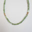 A square faceted green tourmaline beaded necklace with gold beaded accents and lobster clasp. 