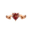 A rose gold ring with a pink heart shaped diamond center stone. Featuring curved design with two garnet accent stones. 