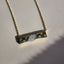 Product picture of a gold rectangle bar pendant with scattered diamonds. The bar is attached to a chain. 