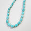 A strand of blue amazonite gemstone necklace with gold bead spacer between each stone. Finished with a wheel clasp.