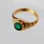 A emerald signet ring with an oval shaped emerald face and ribbed band. The emerald is bezel set into the frame. 