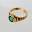 A emerald signet ring with an oval shaped emerald face and ribbed band. The emerald is bezel set into the frame. 