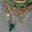 Product picture of a gold dragon pendant with the body a set of emerald gemstone. The dragon's head is turned to the left and body making an S shaped curve. 