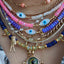 Styling three beaded evil eye necklaces along with other pendants and charms.