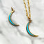 Product picture of a solid gold moon with turquoise colored inlay. The crescent moon is thin and elongated with a bail.