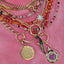 Picture of a necklace layering stack with our ruby heart pendant among other charms and chains.