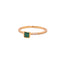 Product picture of a dainty gold band with a princess cut emerald bezel set with two small stones on on side of the band. 